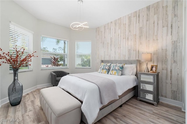 bedroom featuring an inviting chandelier and light wood-type flooring