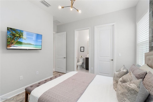 bedroom with connected bathroom, a chandelier, and light hardwood / wood-style flooring