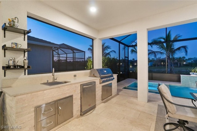 patio terrace at dusk featuring an outdoor kitchen, a grill, a lanai, and sink