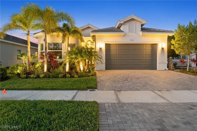 view of front facade featuring a garage, decorative driveway, and stucco siding