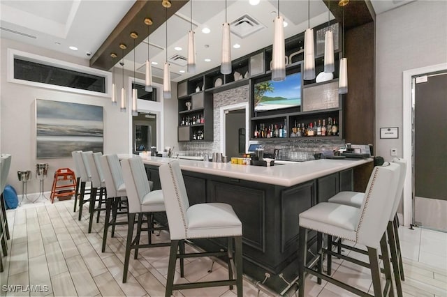 bar featuring tasteful backsplash, indoor wet bar, hanging light fixtures, and visible vents