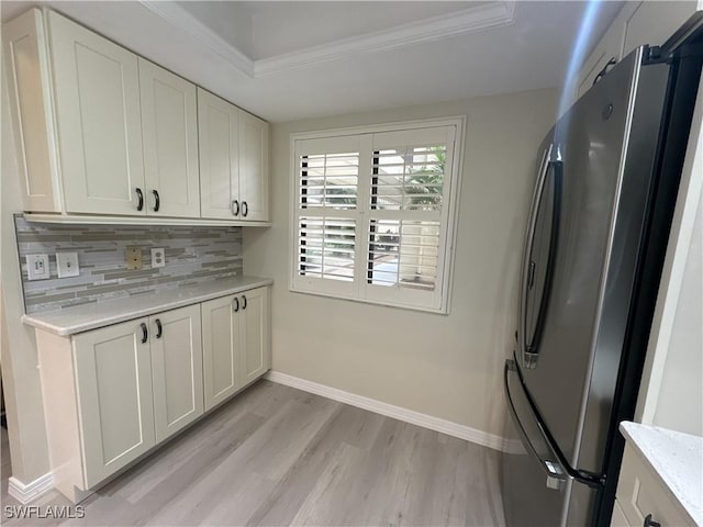 kitchen featuring decorative backsplash, a raised ceiling, light wood-type flooring, stainless steel refrigerator, and white cabinets