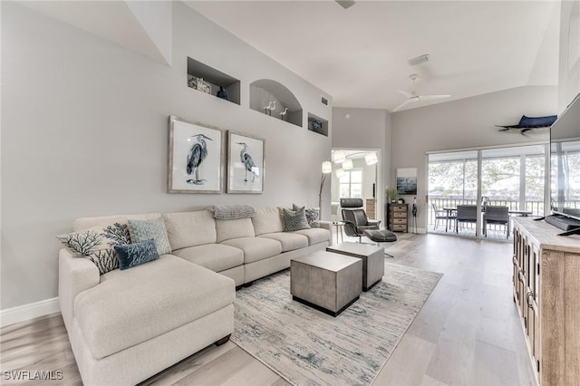 living room featuring a towering ceiling, light hardwood / wood-style floors, and ceiling fan