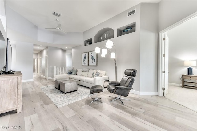 living room featuring a high ceiling, ceiling fan, and light wood-type flooring