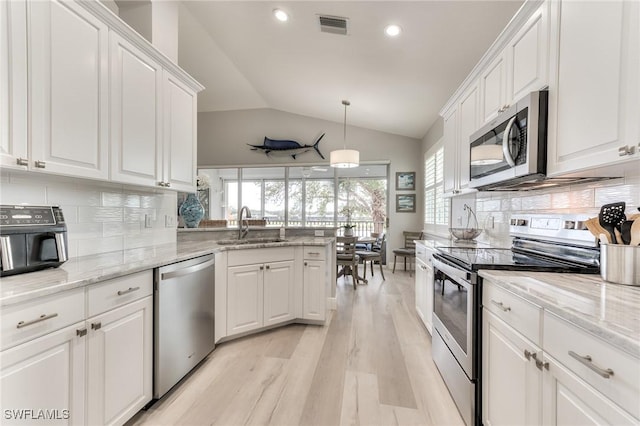 kitchen with appliances with stainless steel finishes, sink, white cabinets, hanging light fixtures, and kitchen peninsula