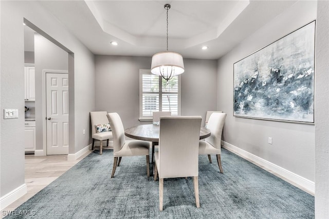 dining area featuring light hardwood / wood-style flooring and a tray ceiling