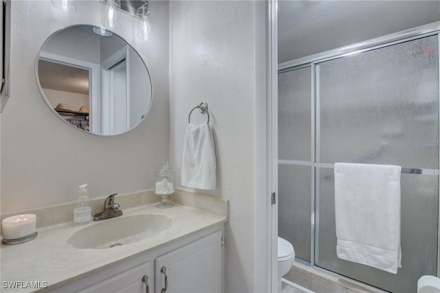 bathroom with toilet, a shower with shower door, and vanity