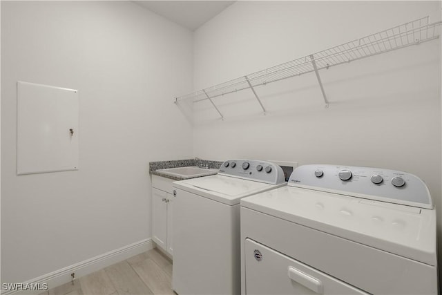 laundry area featuring cabinets, sink, independent washer and dryer, and light wood-type flooring