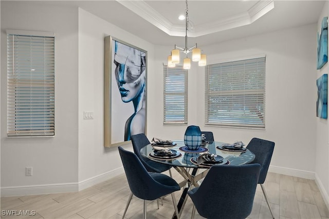 dining area featuring ornamental molding, a raised ceiling, and a notable chandelier