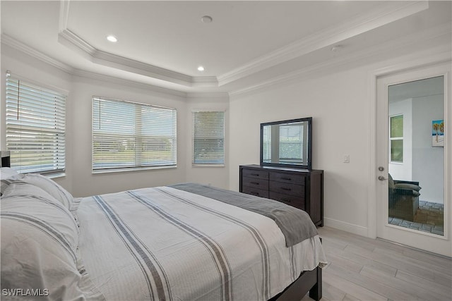 bedroom featuring a tray ceiling, light hardwood / wood-style flooring, and ornamental molding