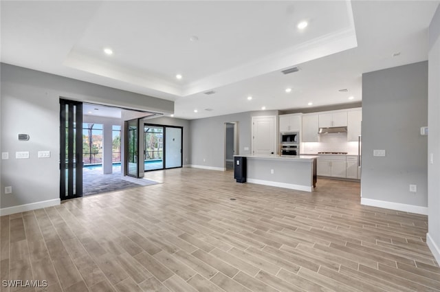 unfurnished living room with a raised ceiling and light hardwood / wood-style flooring