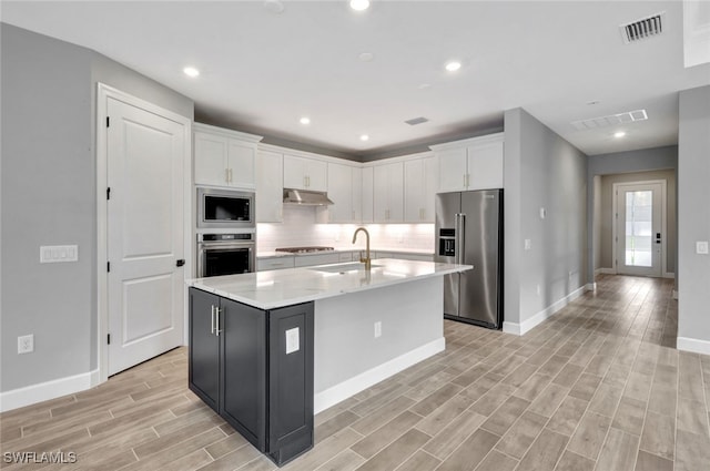 kitchen featuring sink, white cabinetry, stainless steel appliances, and an island with sink