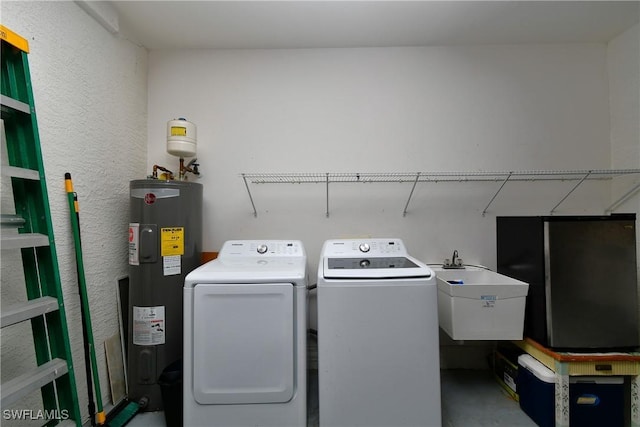 laundry area featuring laundry area, water heater, a sink, and independent washer and dryer