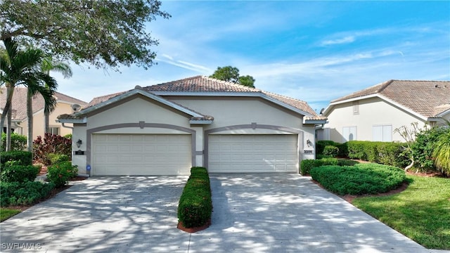 view of front of home with a garage, a tile roof, concrete driveway, and stucco siding