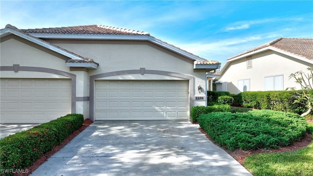 view of front facade featuring a garage, a tile roof, concrete driveway, and stucco siding