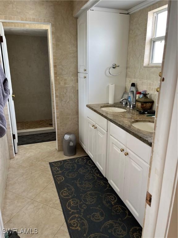 bathroom with a shower, tile walls, ornamental molding, vanity, and tile patterned flooring