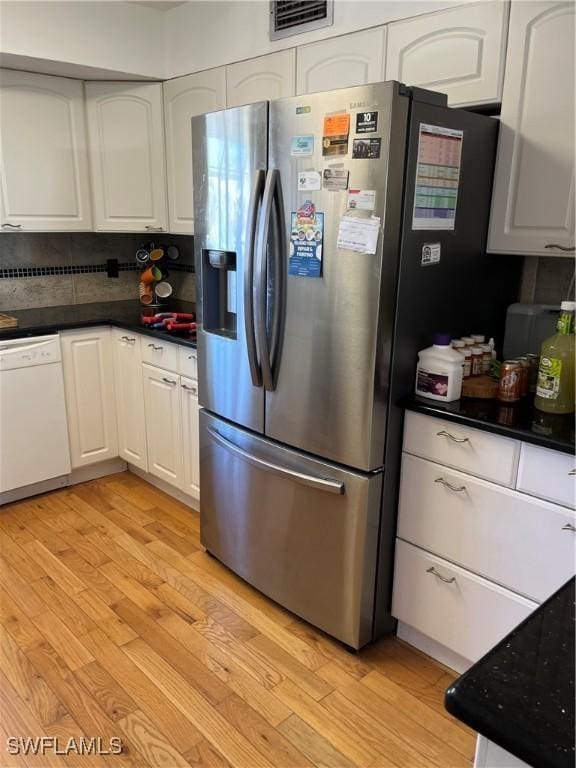 kitchen with dark countertops, stainless steel refrigerator with ice dispenser, white dishwasher, and white cabinets