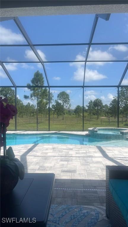 view of swimming pool featuring a lanai, a patio area, and an in ground hot tub