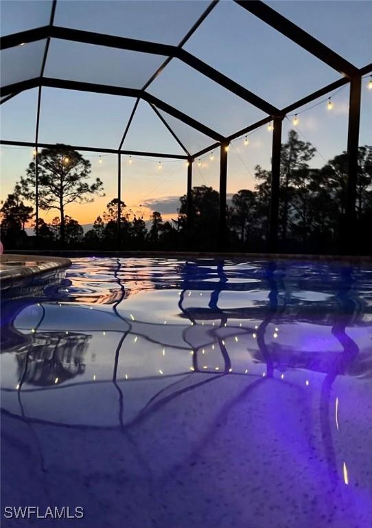 pool at dusk featuring a lanai