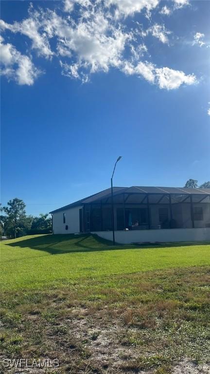 rear view of house featuring a lawn and glass enclosure