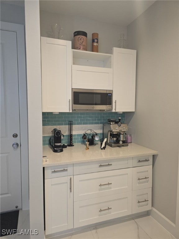 kitchen featuring light tile patterned floors, white cabinetry, and tasteful backsplash