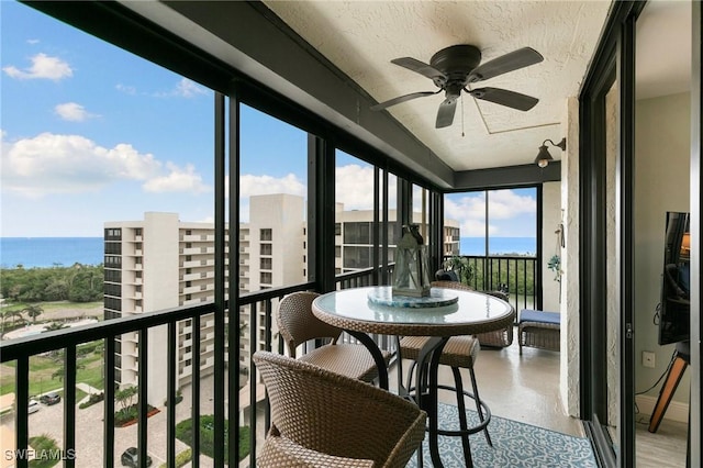 sunroom / solarium with ceiling fan and a water view