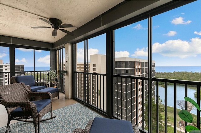 sunroom featuring ceiling fan and a water view