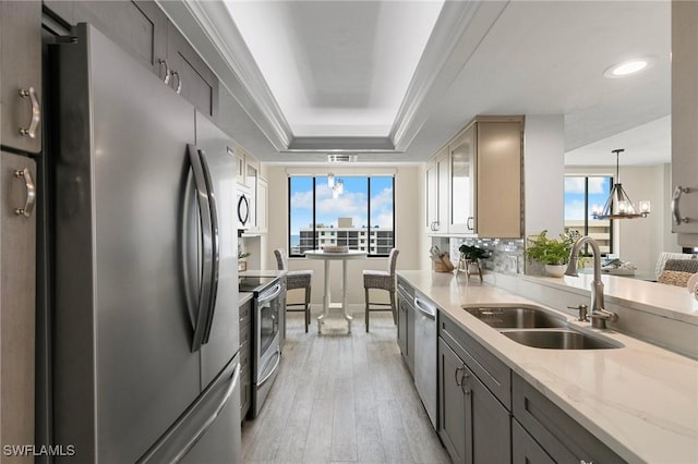 kitchen featuring light stone countertops, a wealth of natural light, appliances with stainless steel finishes, sink, and a raised ceiling