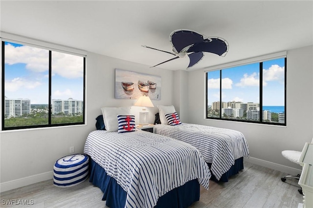 bedroom with ceiling fan, wood-type flooring, and a water view