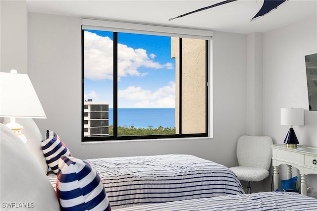 bedroom featuring a water view, ceiling fan, and multiple windows