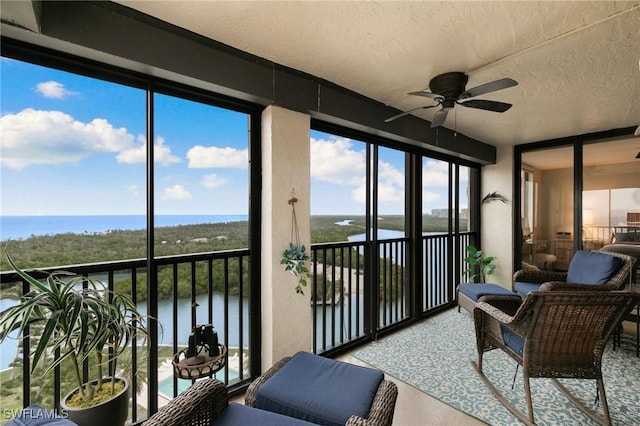 sunroom / solarium featuring ceiling fan, a water view, and a healthy amount of sunlight