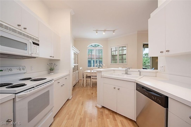 kitchen featuring white appliances, light wood-type flooring, crown molding, white cabinets, and sink