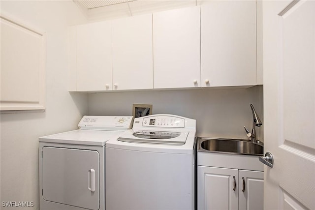 laundry room with sink, washing machine and clothes dryer, and cabinets