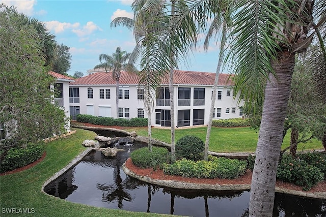 view of home's community with a yard and a small pond