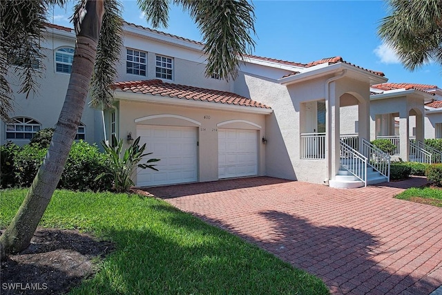 mediterranean / spanish-style home with stucco siding, decorative driveway, and a tile roof