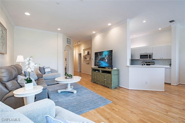 living area featuring crown molding, recessed lighting, light wood-type flooring, arched walkways, and baseboards