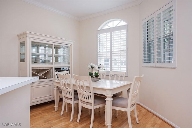 dining area featuring light wood-style flooring, ornamental molding, and baseboards