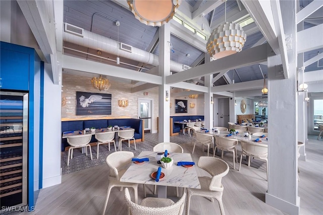 400 L Ambiance Cir Unit 204, Naples, FL 34108 - dining space with wine cooler, wood finished floors, and a towering ceiling