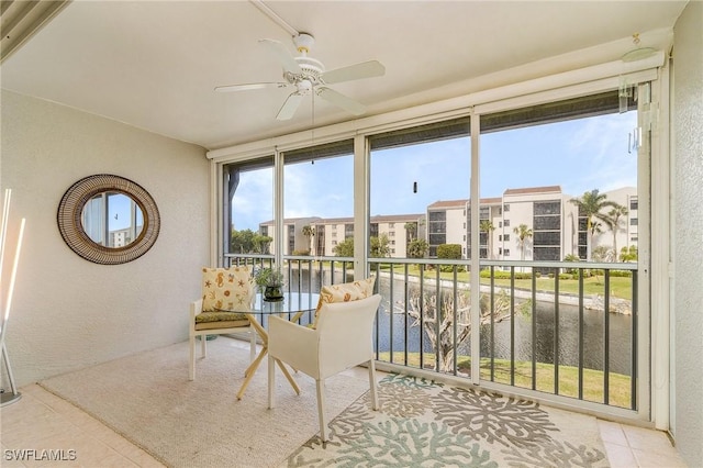 sunroom / solarium featuring ceiling fan and a water view