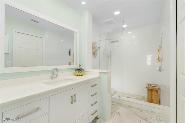 bathroom with vanity, tiled shower, and toilet