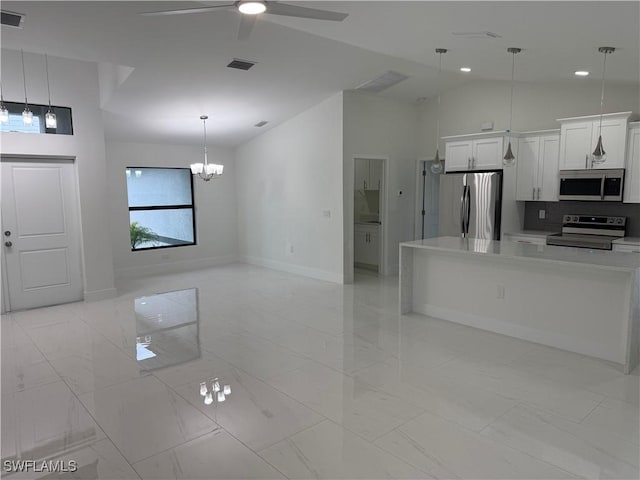 kitchen featuring white cabinetry, appliances with stainless steel finishes, lofted ceiling, hanging light fixtures, and ceiling fan with notable chandelier