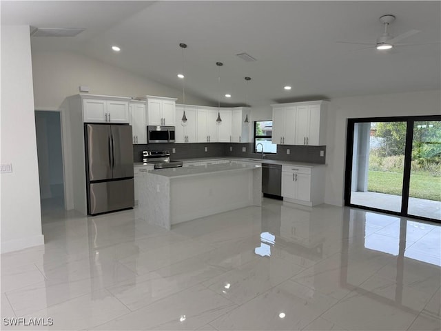 kitchen with tasteful backsplash, lofted ceiling, a kitchen island, stainless steel appliances, and white cabinets