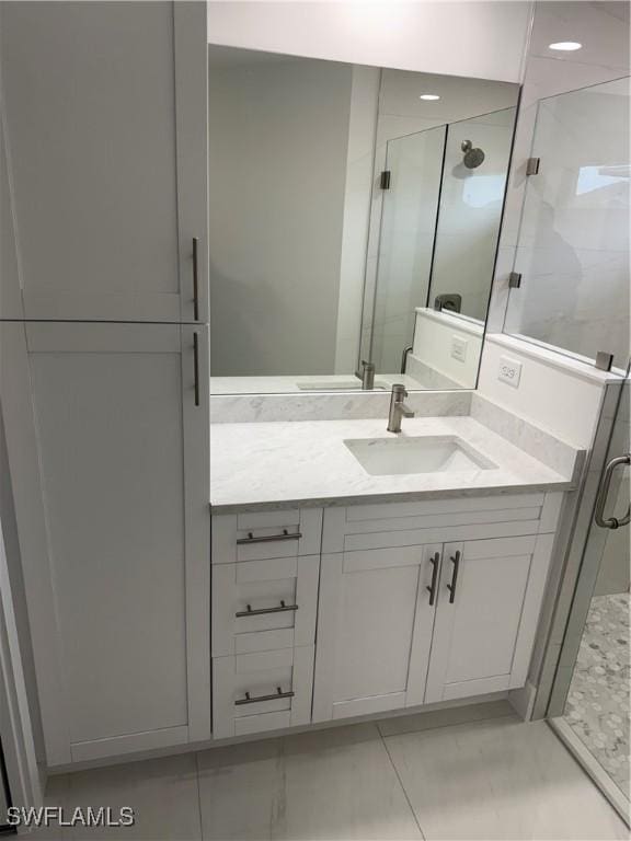 bathroom with a shower with shower door, tile patterned floors, and vanity