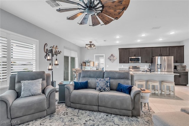 living room featuring ceiling fan, light tile patterned floors, and sink