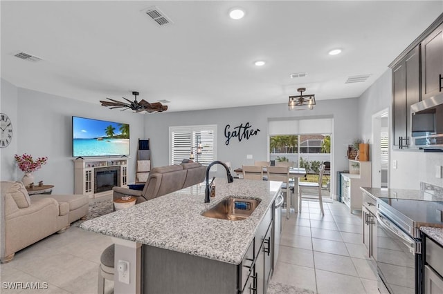 kitchen featuring an island with sink, ceiling fan, appliances with stainless steel finishes, a wealth of natural light, and sink