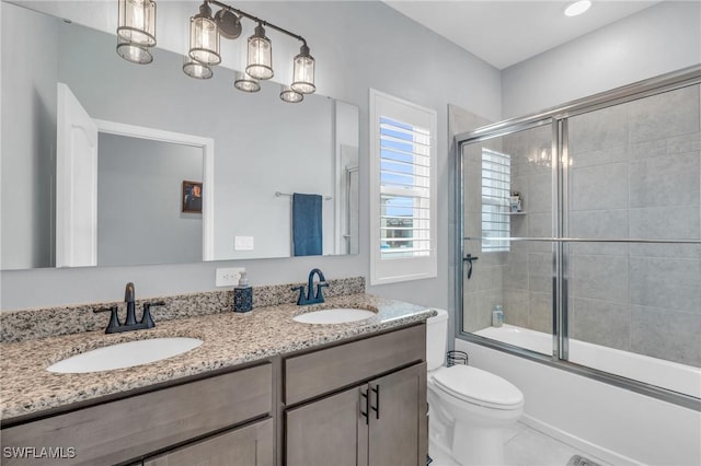 full bathroom featuring toilet, vanity, and shower / bath combination with glass door