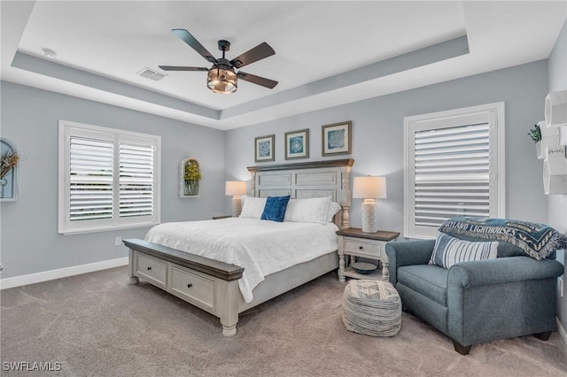 carpeted bedroom featuring ceiling fan and a tray ceiling