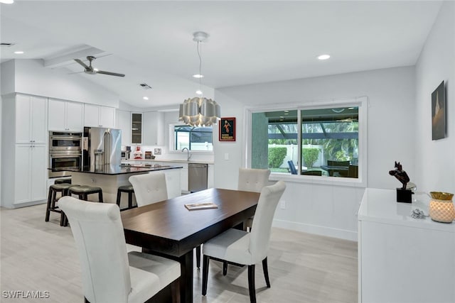 dining space featuring sink, light hardwood / wood-style flooring, lofted ceiling with beams, and ceiling fan