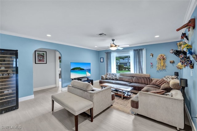 living room with crown molding, ceiling fan, and light wood-type flooring