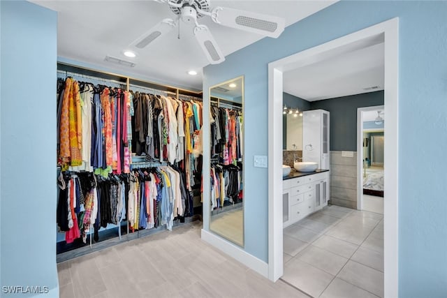 spacious closet with sink, ceiling fan, and light tile patterned flooring